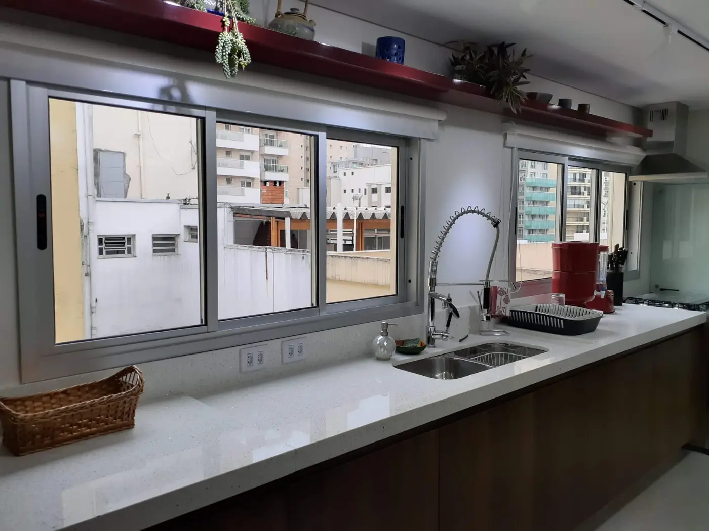 Janela de correr de alumínio sobre bancada de cozinha com vista urbana