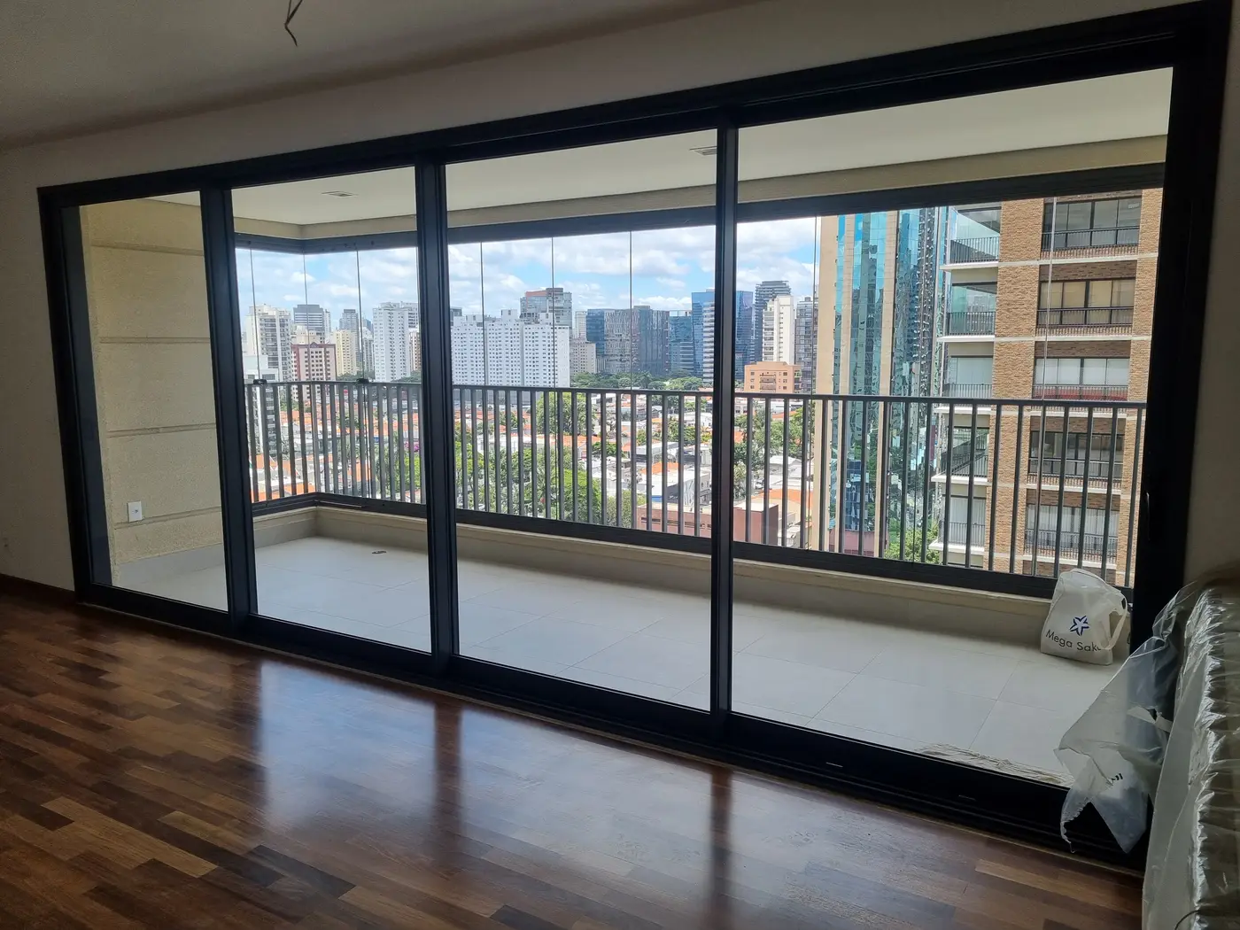 Porta de correr de alumínio com vidro amplo integrando sala e varanda com vista para a cidade