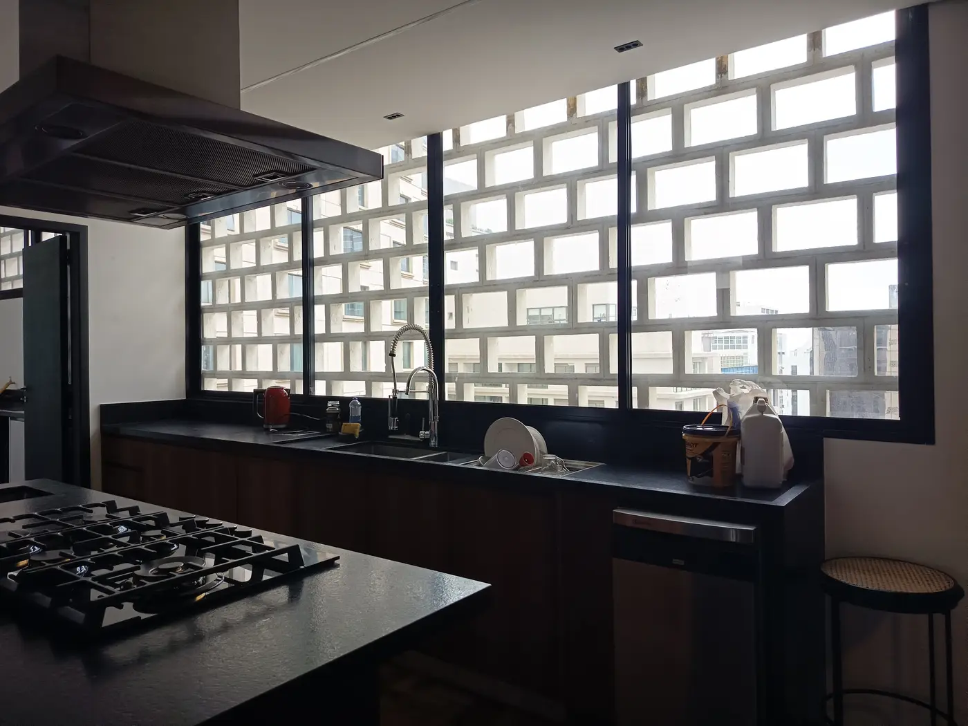 Janela grande com perfil preto em cozinha planejada com bancada e cooktop