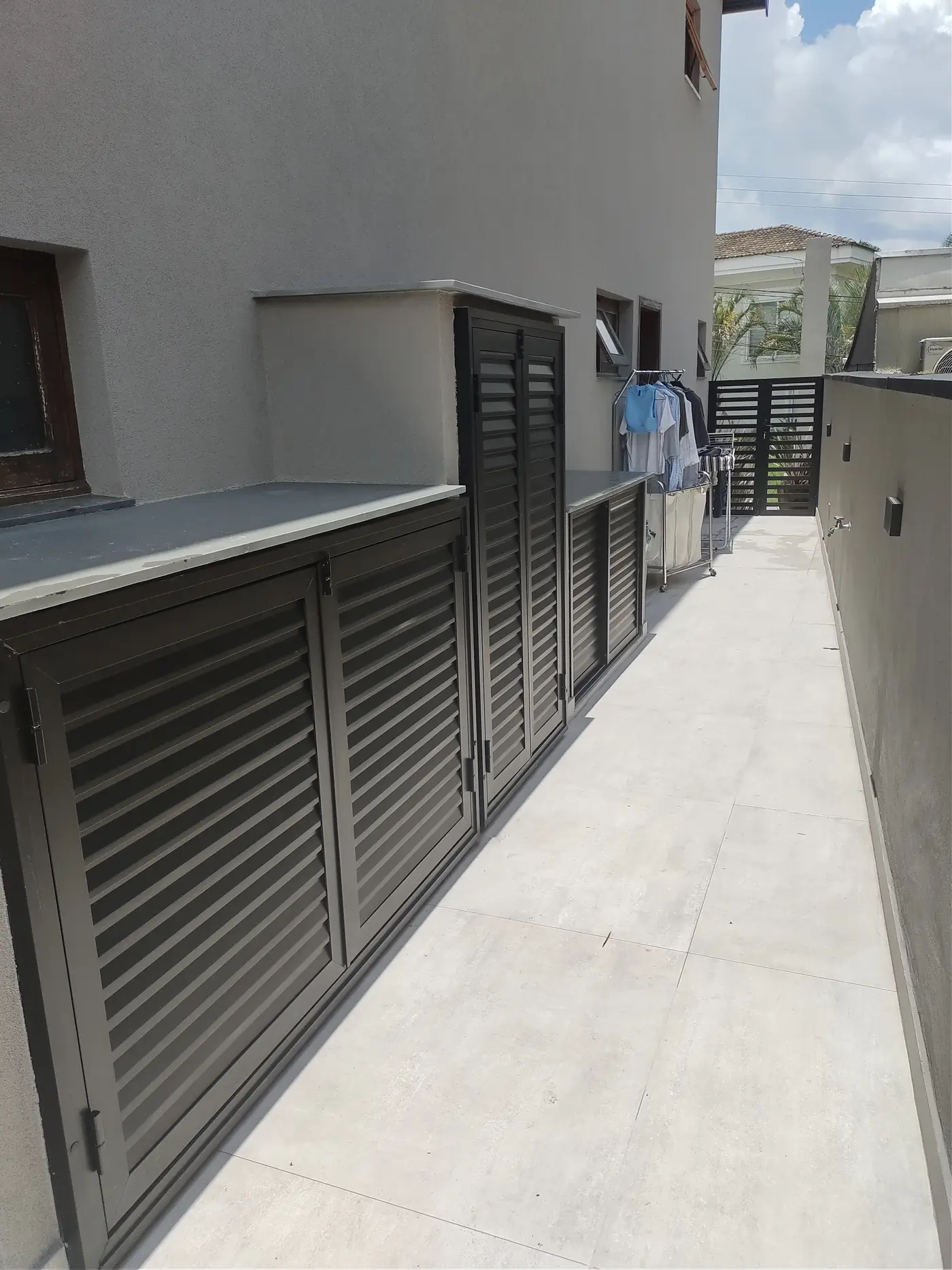Portas venezianas metálicas em corredor lateral de residência