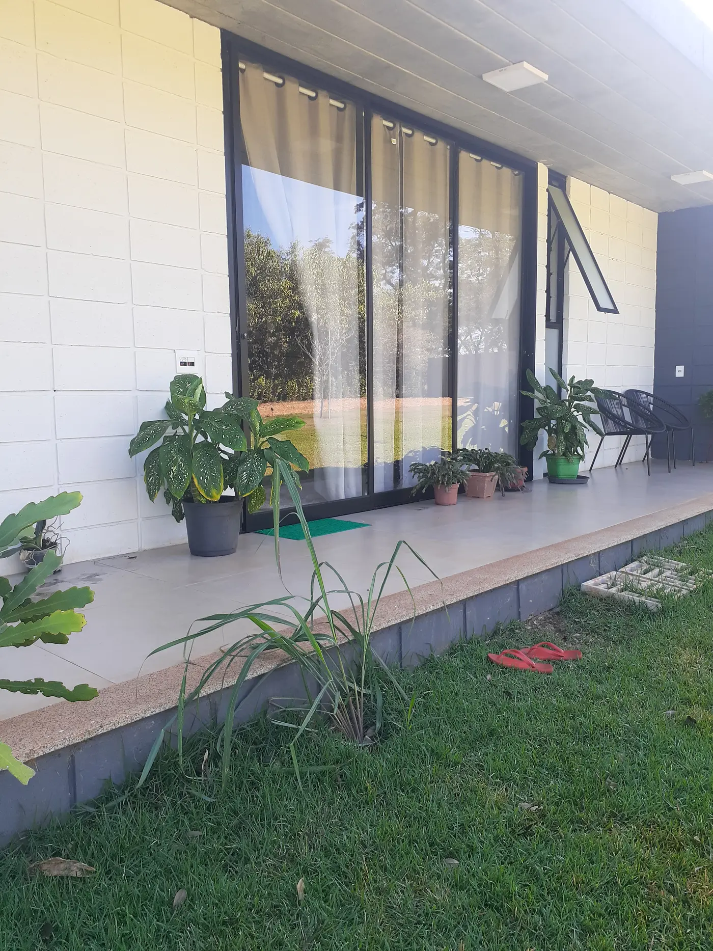 Portas de correr de vidro piso-teto abrindo para o jardim de uma residência